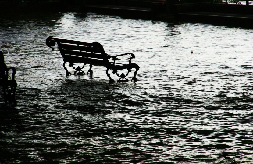 A generic image of a park bench partially submerged by flood water.
